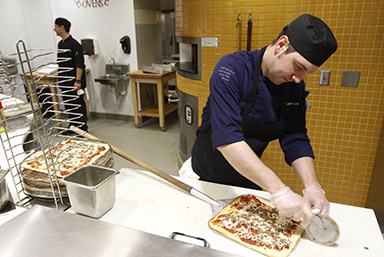Dining staff preparing a brick oven Pizza