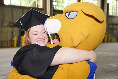 Student at graduation hugging Wildcat Willie