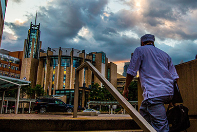 Student walking up stairs towards campus. The sun begins to set.
