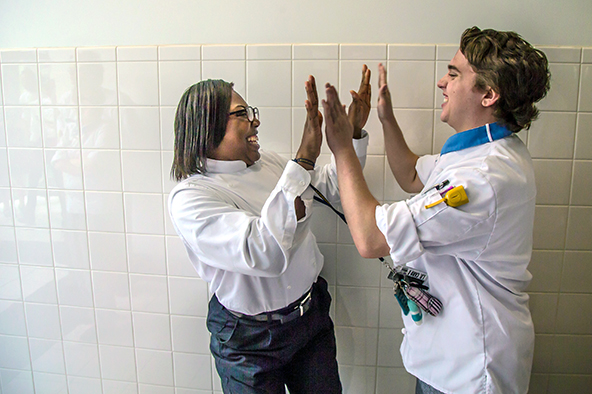 Two students in chef whites double-high-fiving