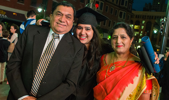 Student at commencement with her parents, holding her degree