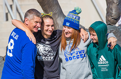 Parents and kids smiling for the camera, celebrating their student's win - women's soccer