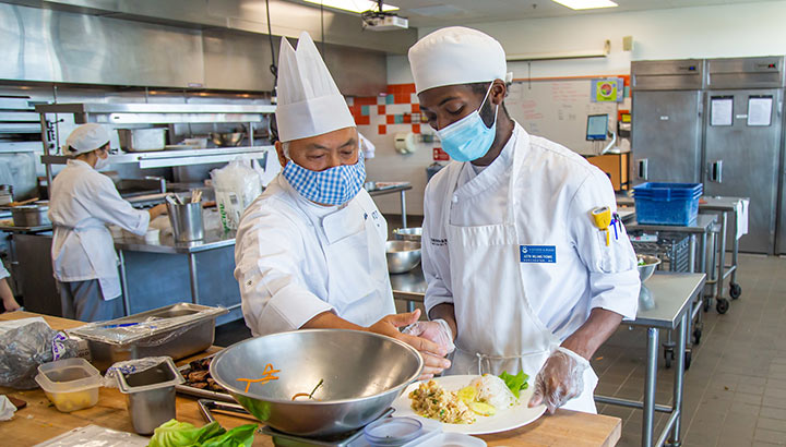 A chef instructing a student in a JWU culinary lab kitchen