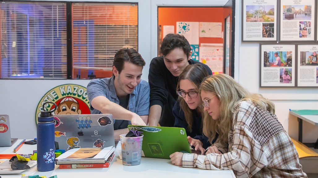 students in art room gathered around a laptop