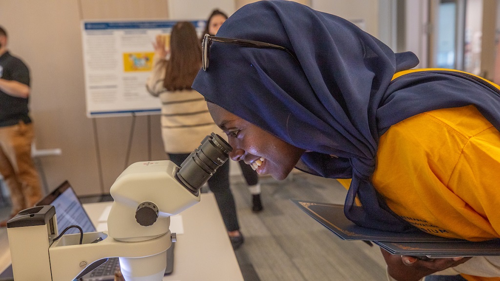 college student looking through microscope