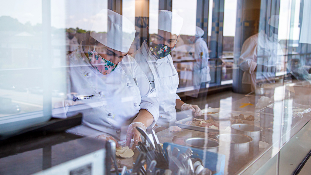 JWU students framed in one of the big picture windows that line the hallways of the Cuisinart Center for Culinary Excellence at JWU’s Providence Campus.