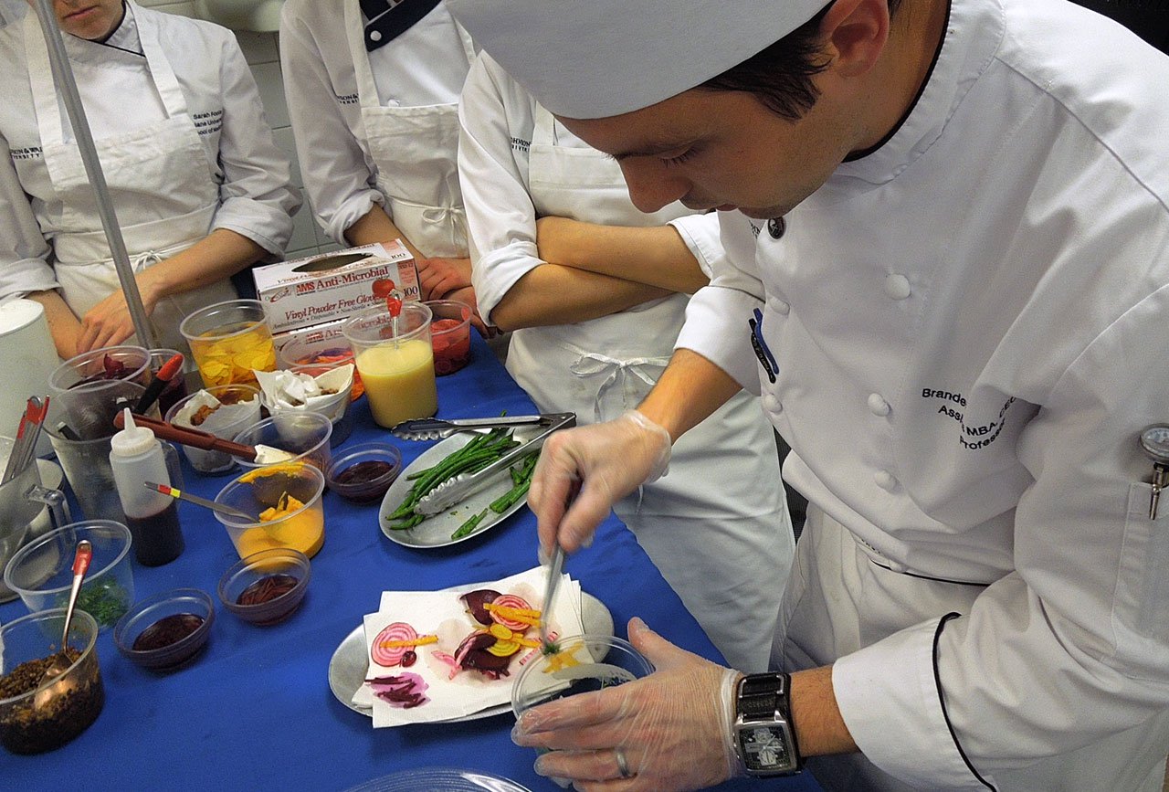 Chef Branden Lewis using tweezers to choose elements for a plate.