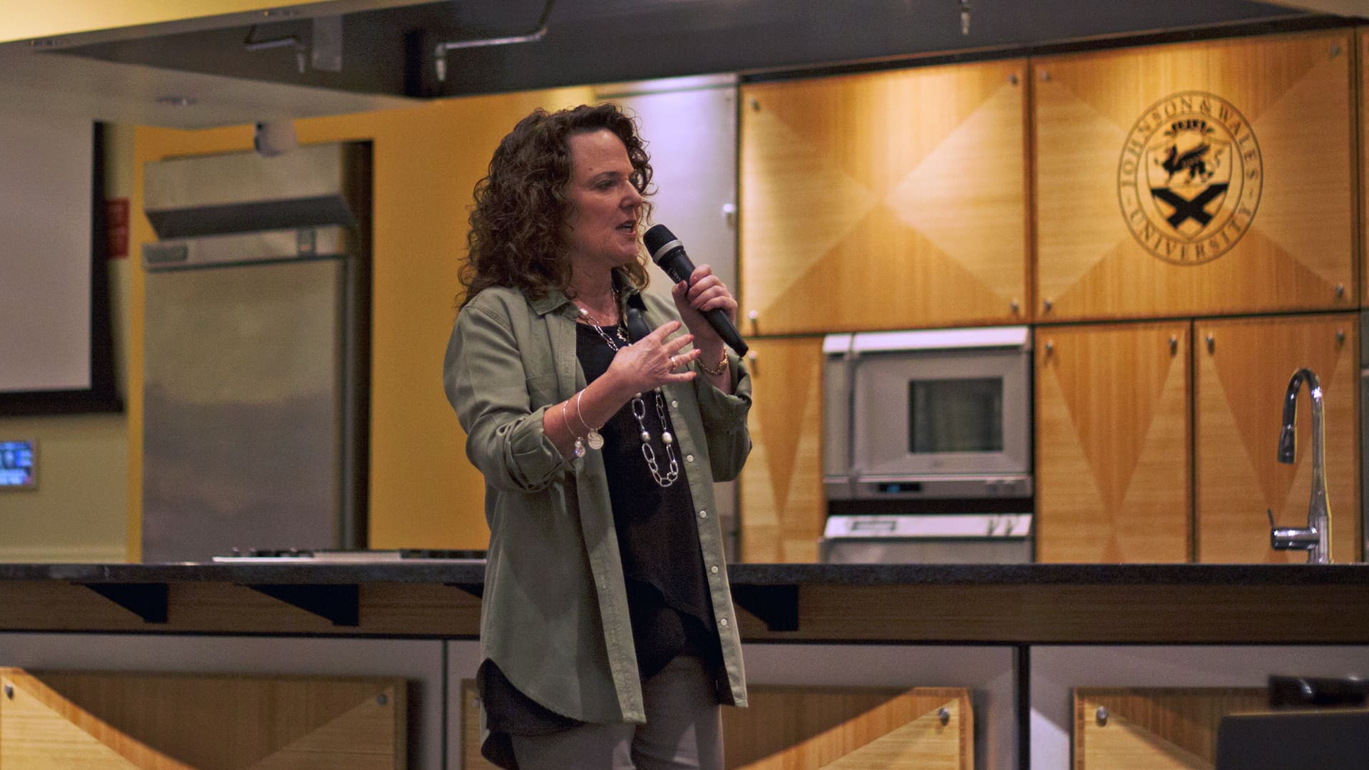 Vitamix CEO Jodi Berg talking on a microphone to JWU students.