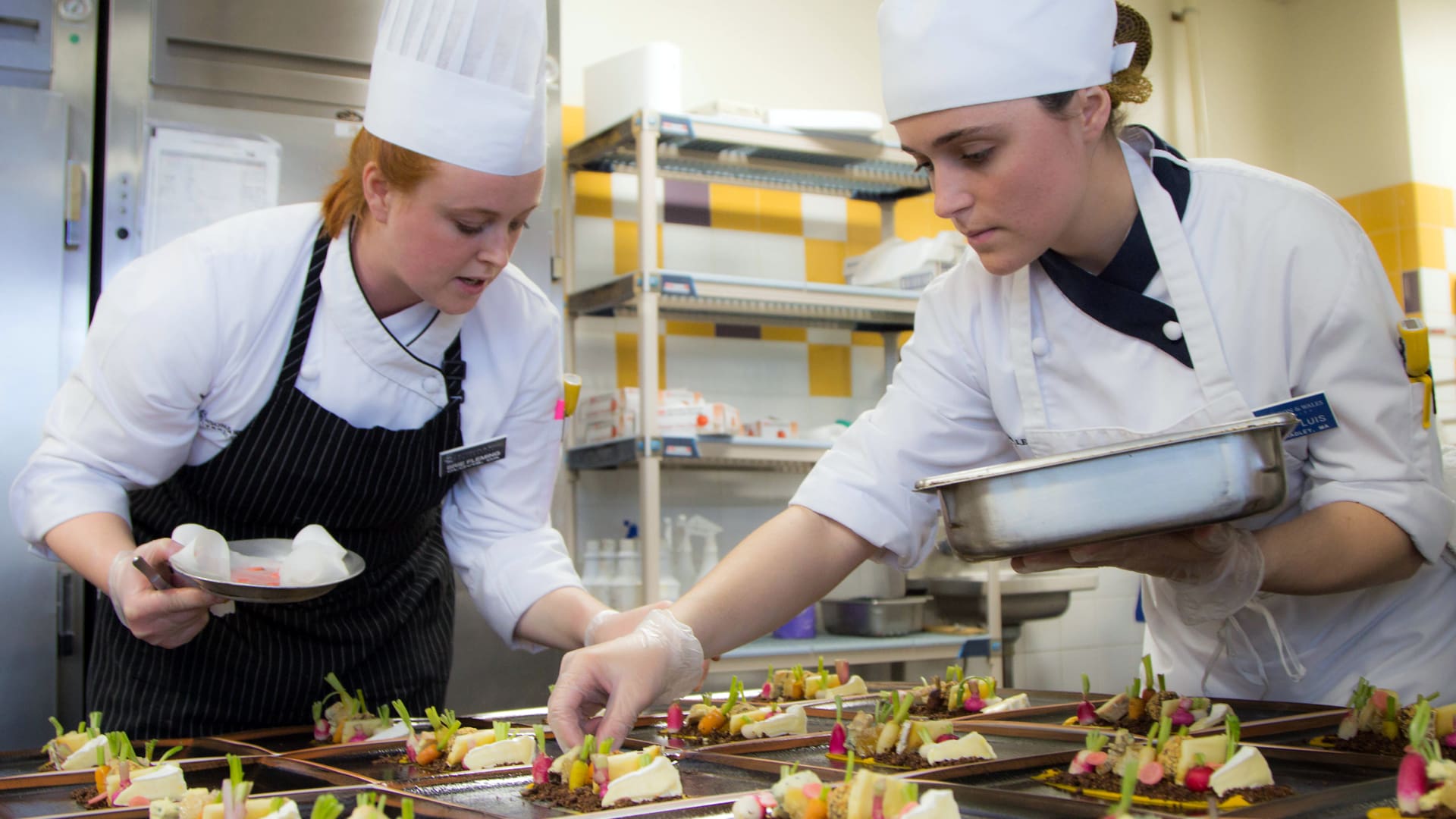 Students put the finishing touches on plated food.