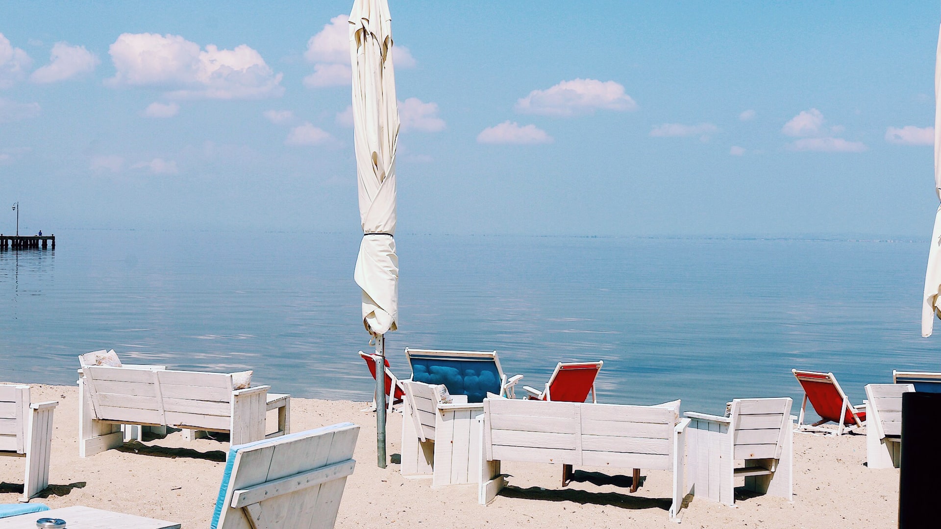 Calm Aegean sea with beach chairs and umbrellas.