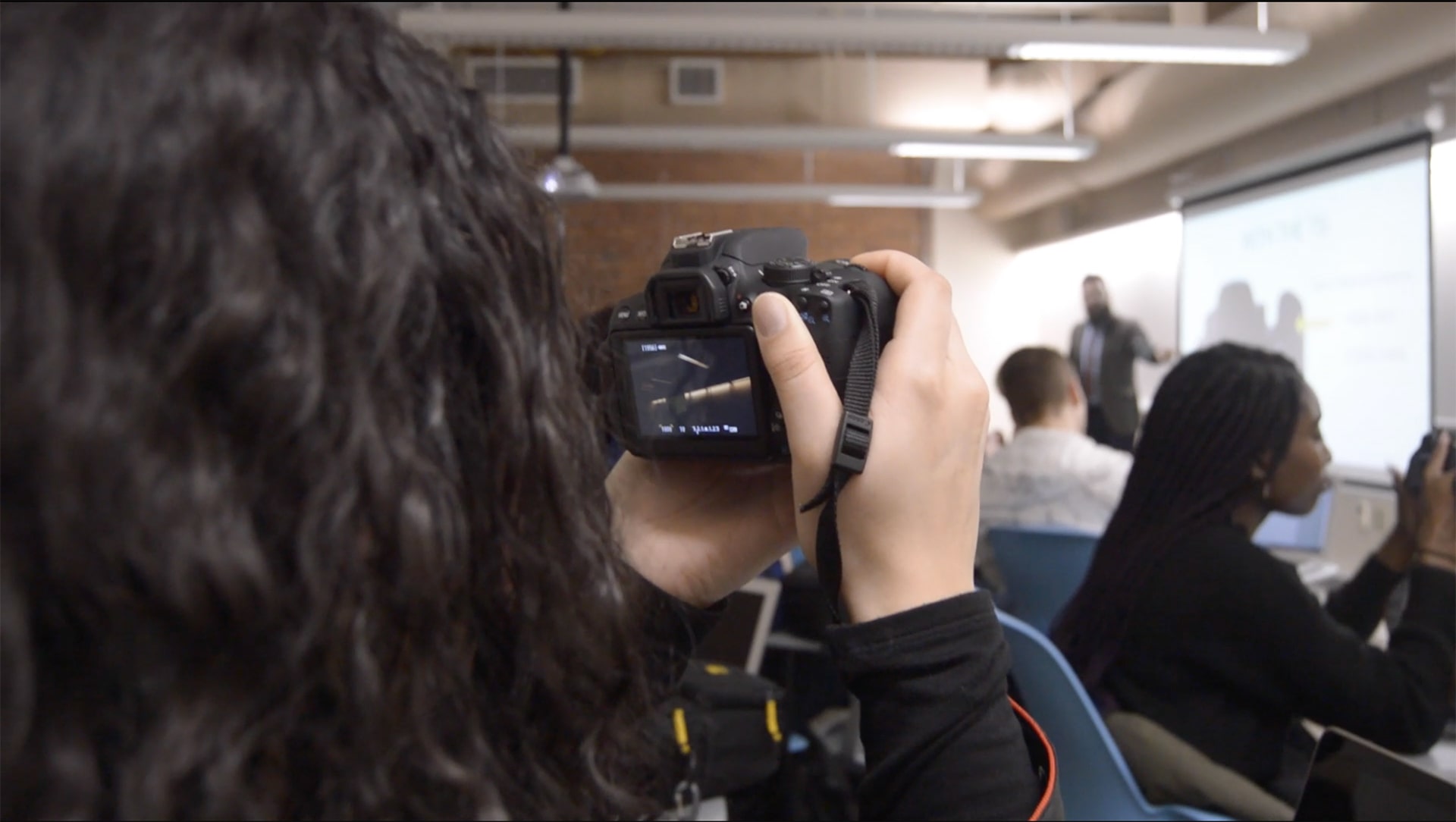 JWU Media Communication student takes picture with camera in class