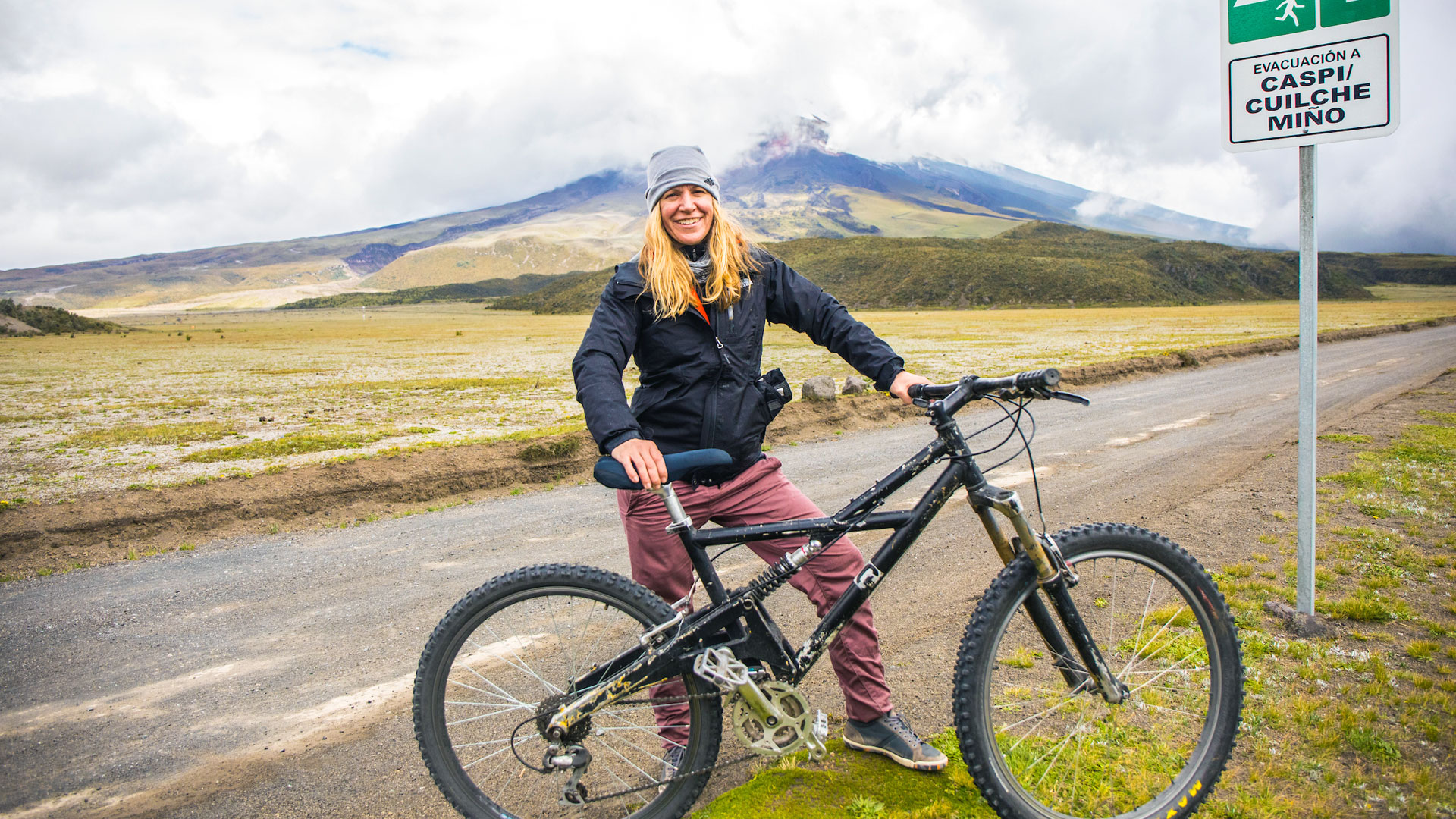 Assistant Professor Tiffany Rhodes, while leading a group mountain bike ride, in front of Cotopaxi volcano
