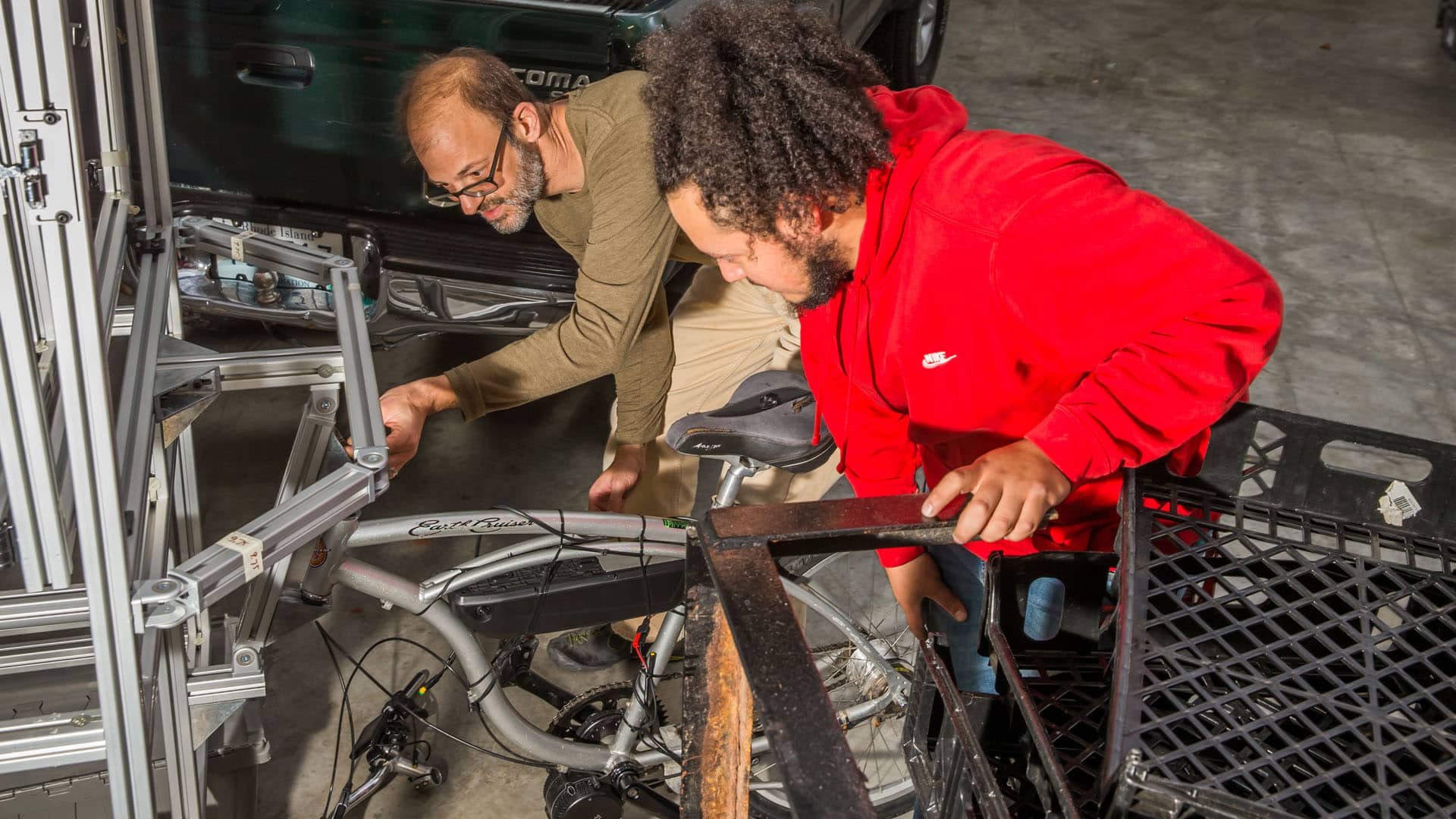 Sebastian Silva 20 works with Associate Professor Jonathan Harris on building the bike food-cart. 