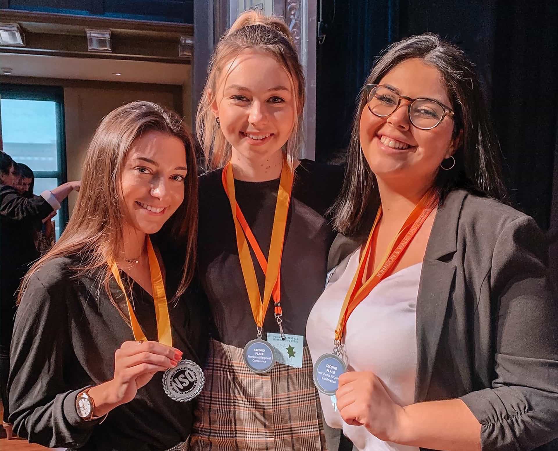 three female students with DECA medals