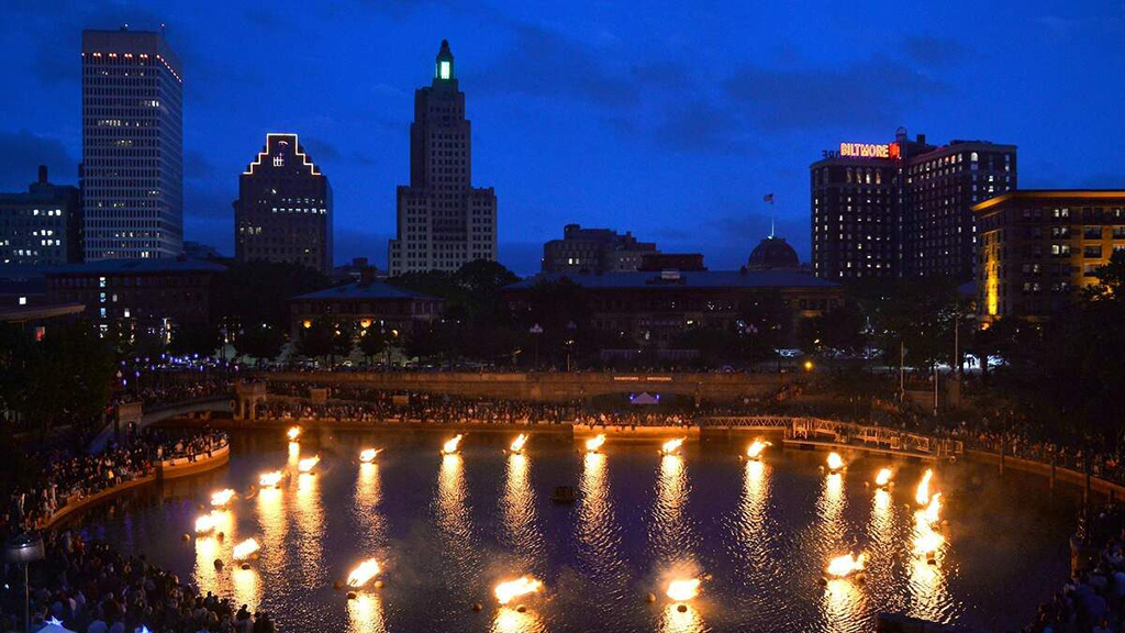 The Providence city skyline at night with flames on the water in the foreground