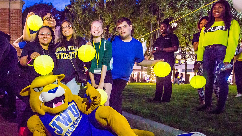 JWU students smile and post with mascot Wildcat Willie at a campus event