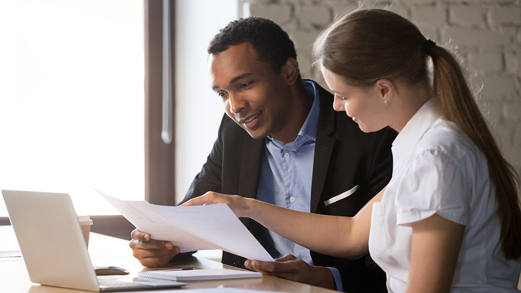 a male financial planner and a female student look together at paperwork