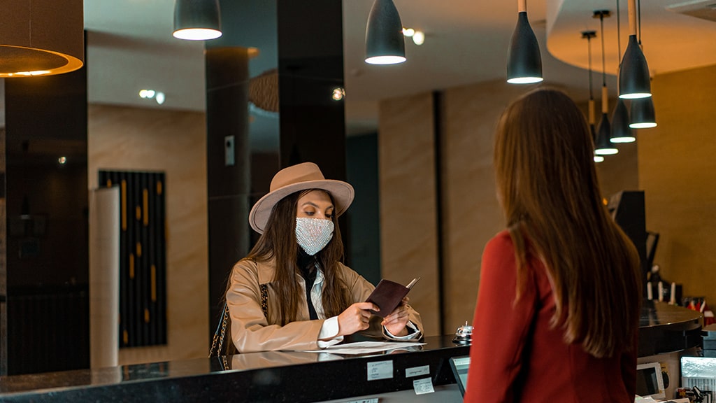 Woman wearing a mask checking in to an hotel