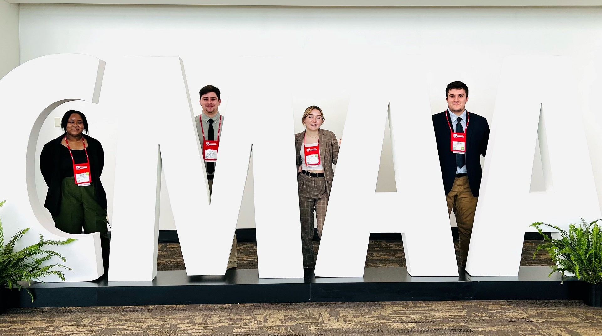 Four JWU students stand in front of sign at conference