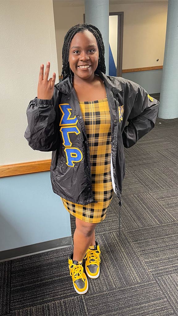 C'Aira Dillard posing for a photo while wearing the Greek letters of her sorority