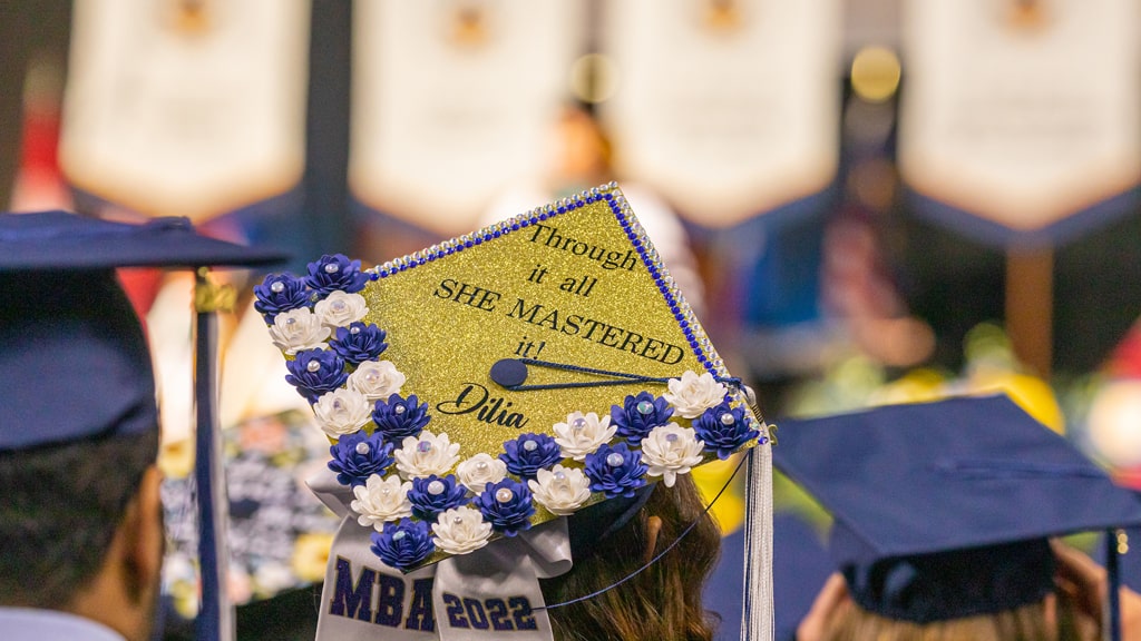 Decorated mortarboard stating, “Through it all, she mastered it!”