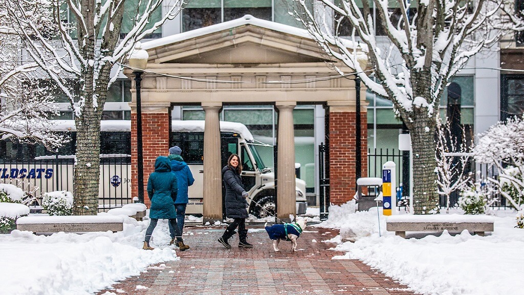 students walking dog on campus in the winter