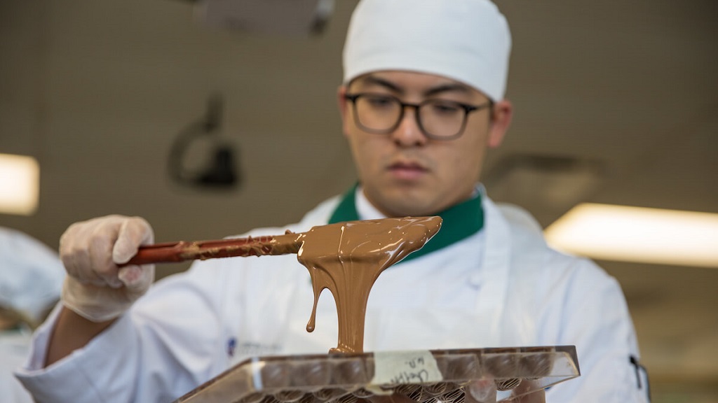 baking student pouring chocolate into mold
