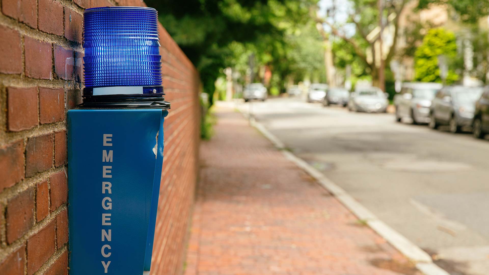 photo showing a blue box labeled EMERGENCY against a brick wall