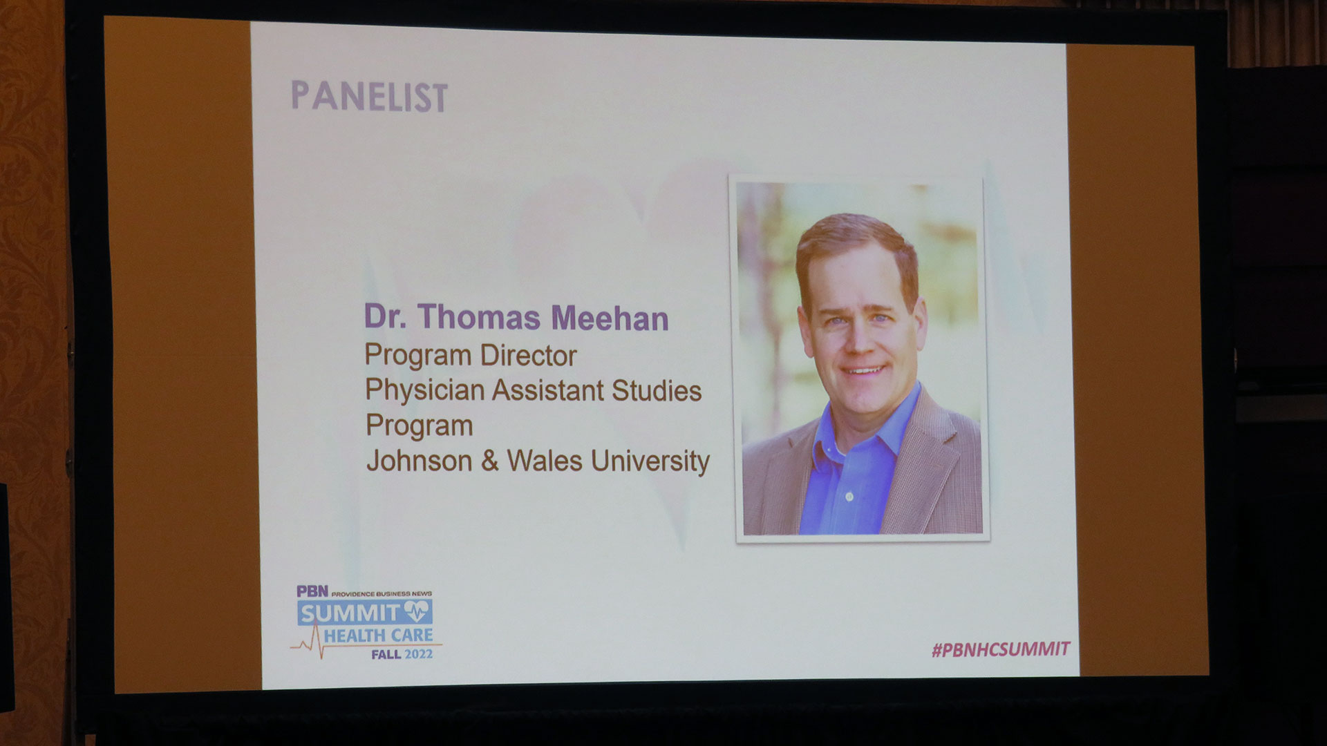 photo capturing a screen at the PBN healthcare summit listing Thomas Meehan as a panelist