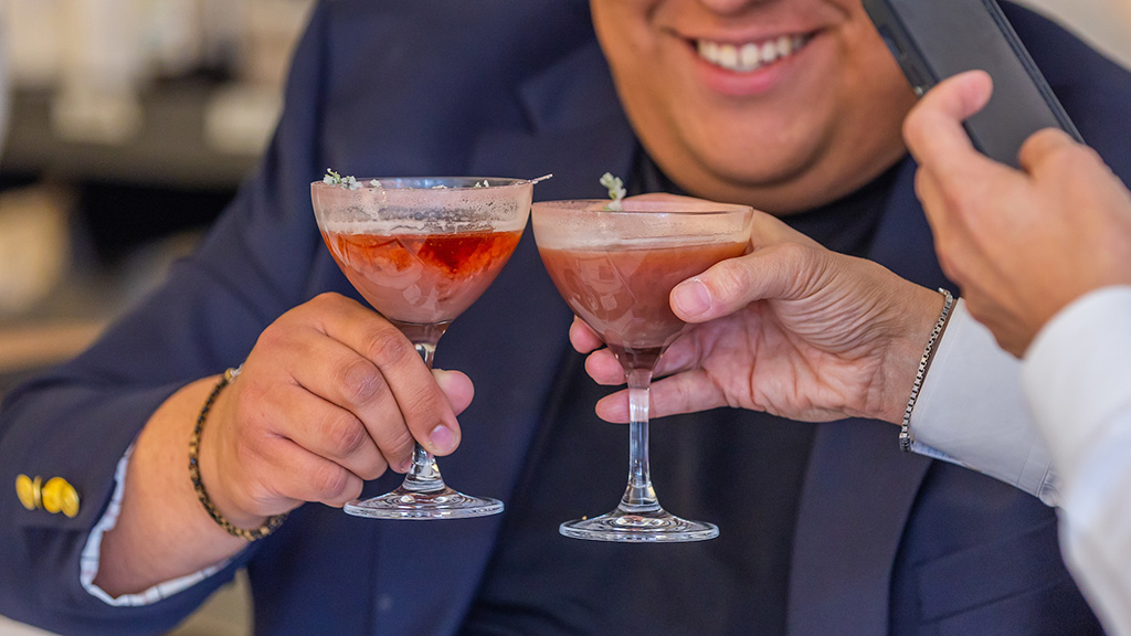 Two men toast with red drinks in glasses