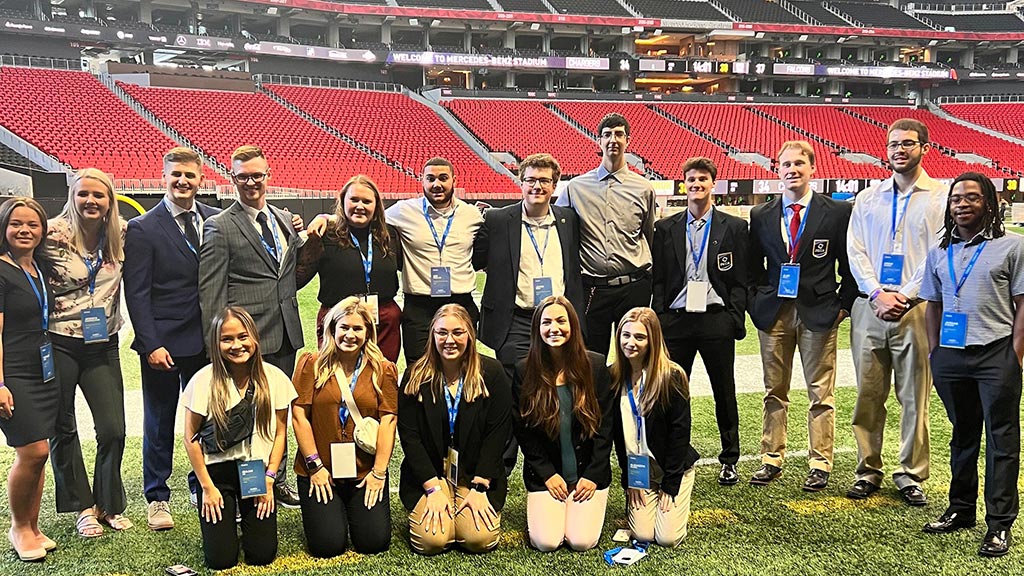 JWU students Asraf Soltani and Mackenzie Weber are among a large group of students posing for a photo at Mercedes Benz stadium in Atlanta, Georgia