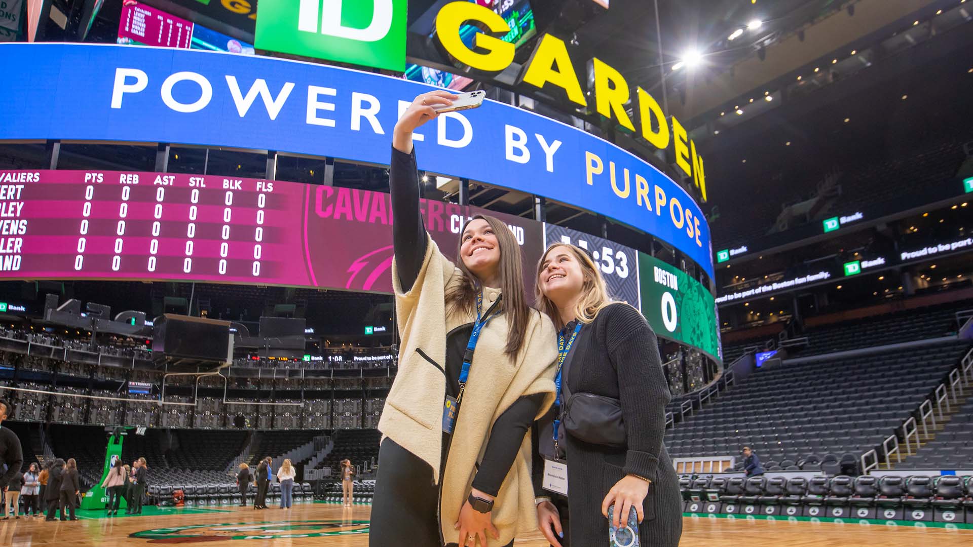 Two students take a selfie in front of the jumbotron at TD Garden