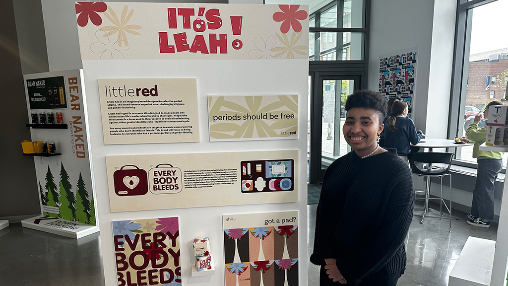 Leah Ward '23 standing next to her senior showcase design project display