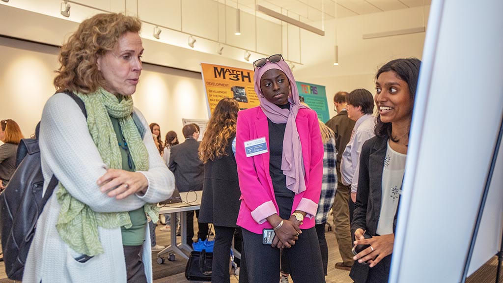 JWU community members listen to and ask questions about students' work at the Symposium.