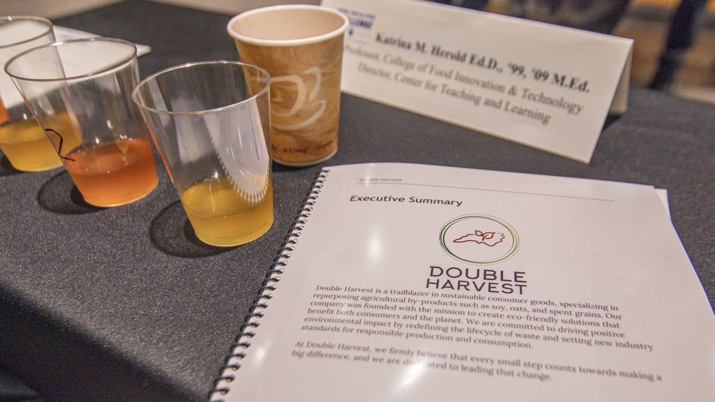 Closeup of plastic cups filled with different styles of mead and the cover of the Double Harvest business plan.