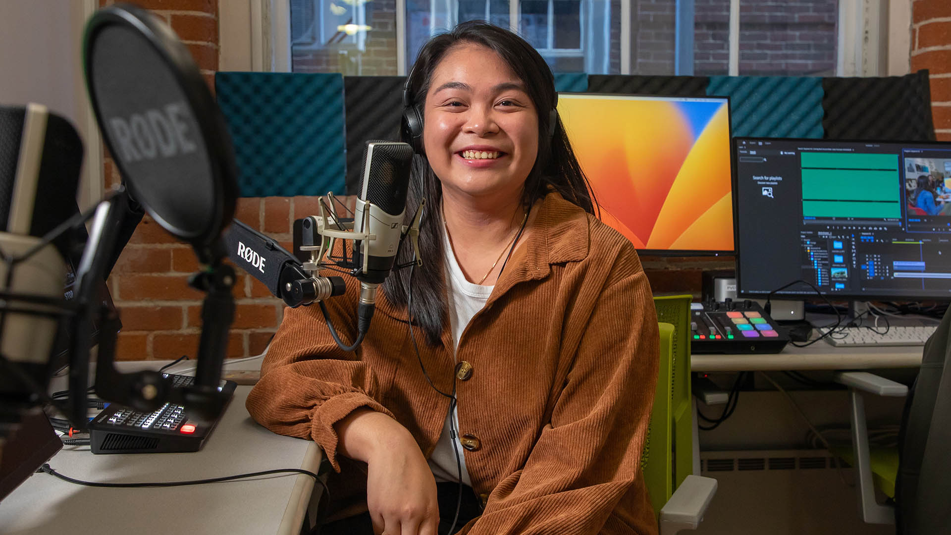 Hillary Thilavong '23 smiling from a production booth in JWU's Center for Media Production