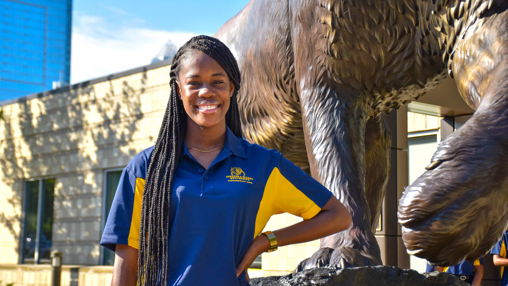 Hopal Richards '24 poses smiling in front of the JWU Charlotte wildcat statue