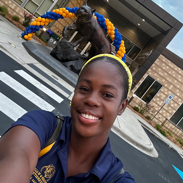 Dressed in blue and yellow, Hopal Richards '24 takes a selfie on JWU's Charlotte Campus