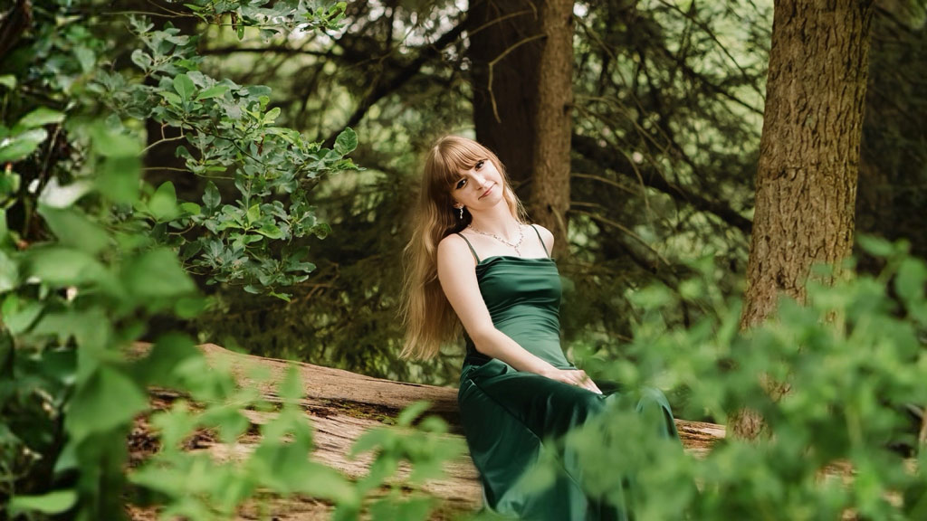 a photo of Ariana Adolph '28 posing while in a forest setting
