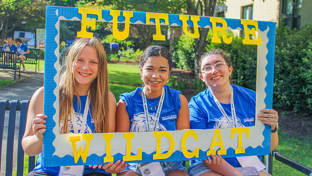 New students pose with a photo prop - a giant blue and yellow photo frame that reads 'Future Wildcat.'