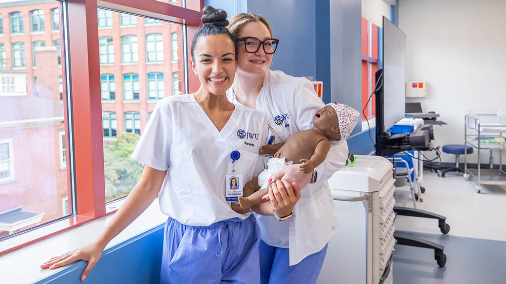 Kelsey Quinlan (left) with another nursing student and an infant mannequin in the nursing simulation lab.
