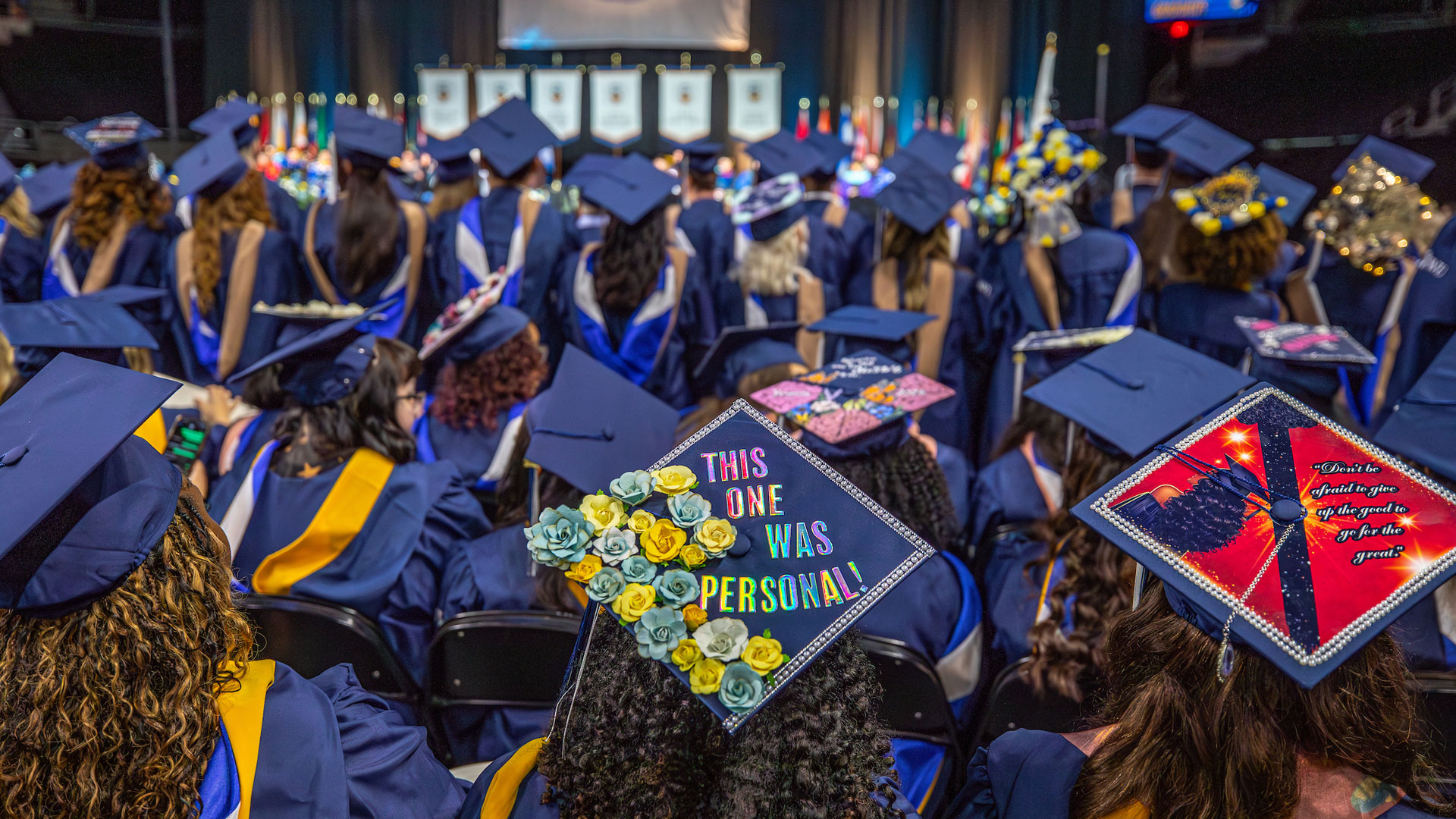 Sea of decorated mortarboards, including one eblazoned with “This one was personal.”