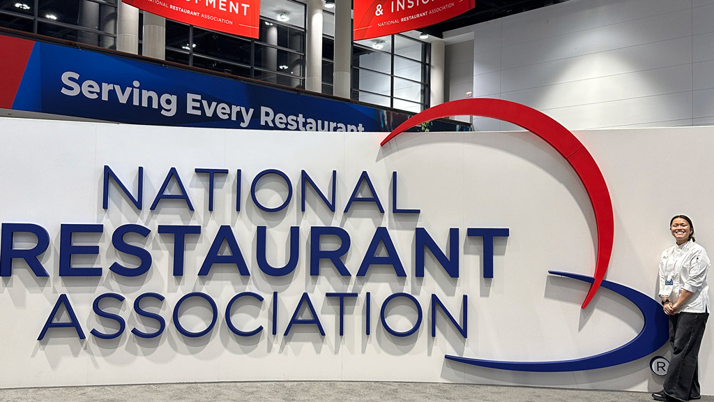 photo of Madison Chan '26 posing by a giant National Restaurant Association sign