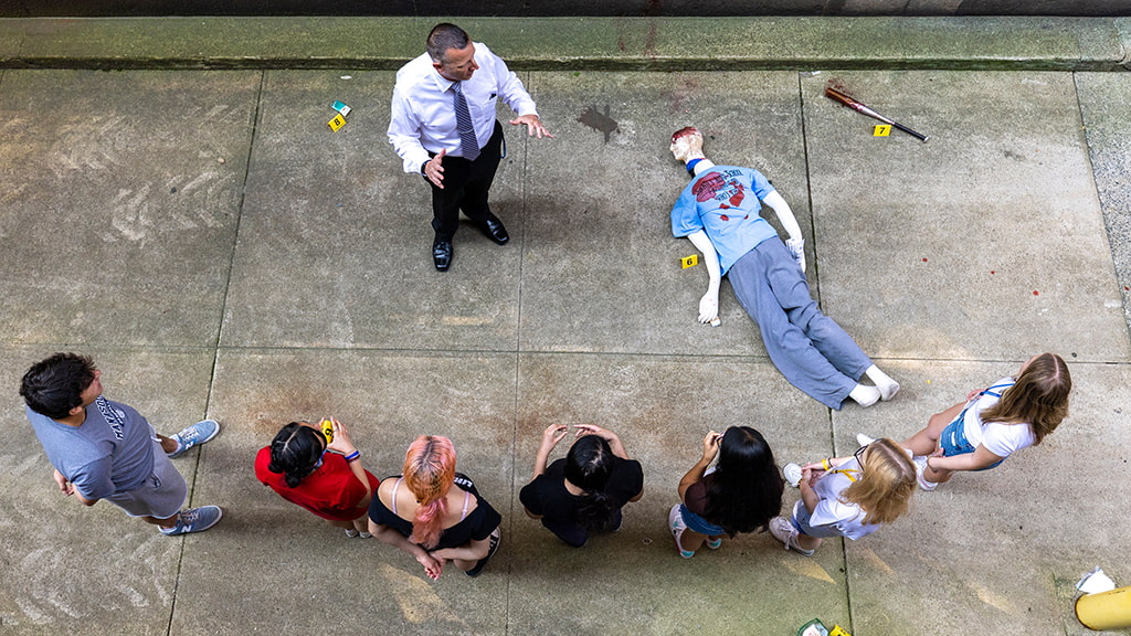 Aerial shot of Criminal Justice CX students and professor by a staged crime scene