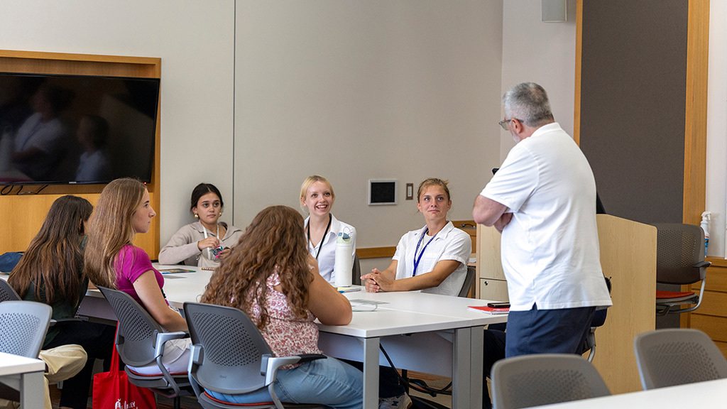 A professor lectures to a seated group of Health &amp; Wellness CX students