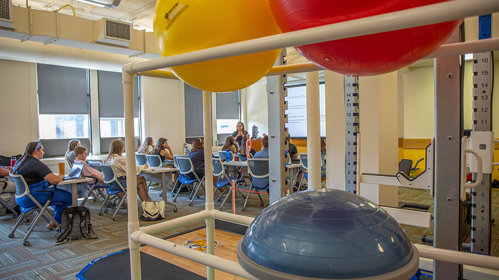 A classroom full of JWU CX students watch a professor lecture about nutrition