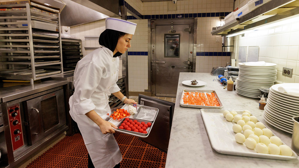 photo of Fatima Khan '27 working with trays of food in a kitchen