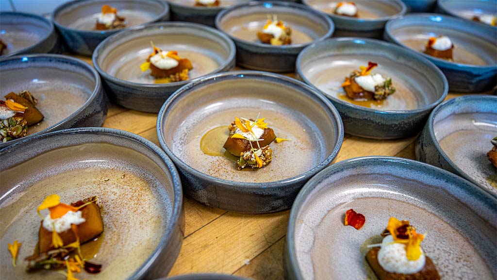 Plated dessert dishes arranged on a table, each featuring a small portion topped with cream and garnished with edible flowers.
