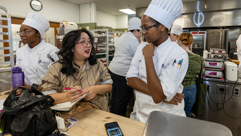 A design students talking with a culinary student in the kitchen