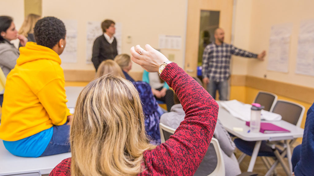 A student raises a hand during a lecture. 